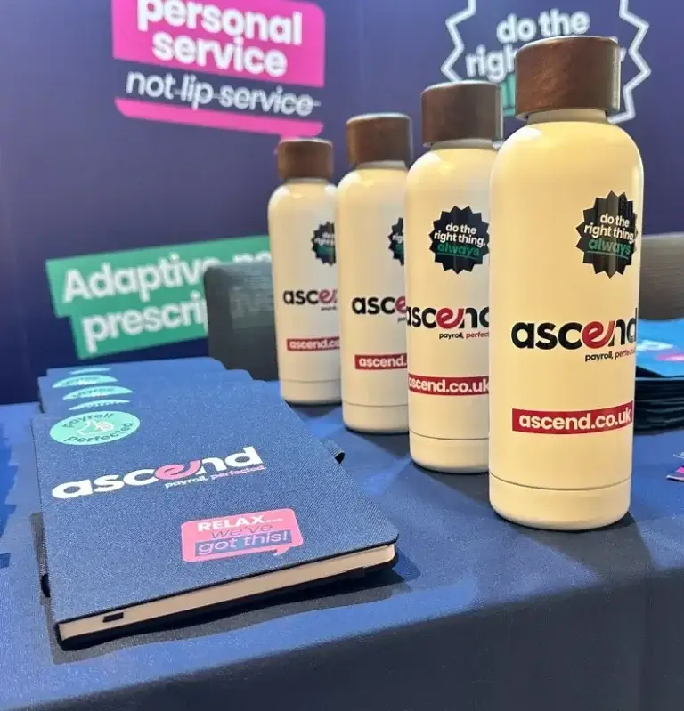 Ascend payroll themed bottles and notepads on a table