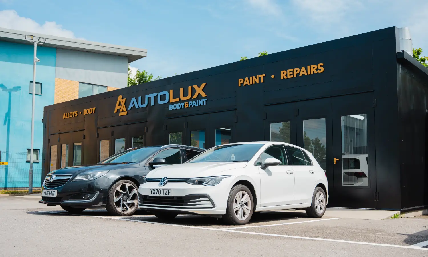 Autolux branded workshop with two cars at the front