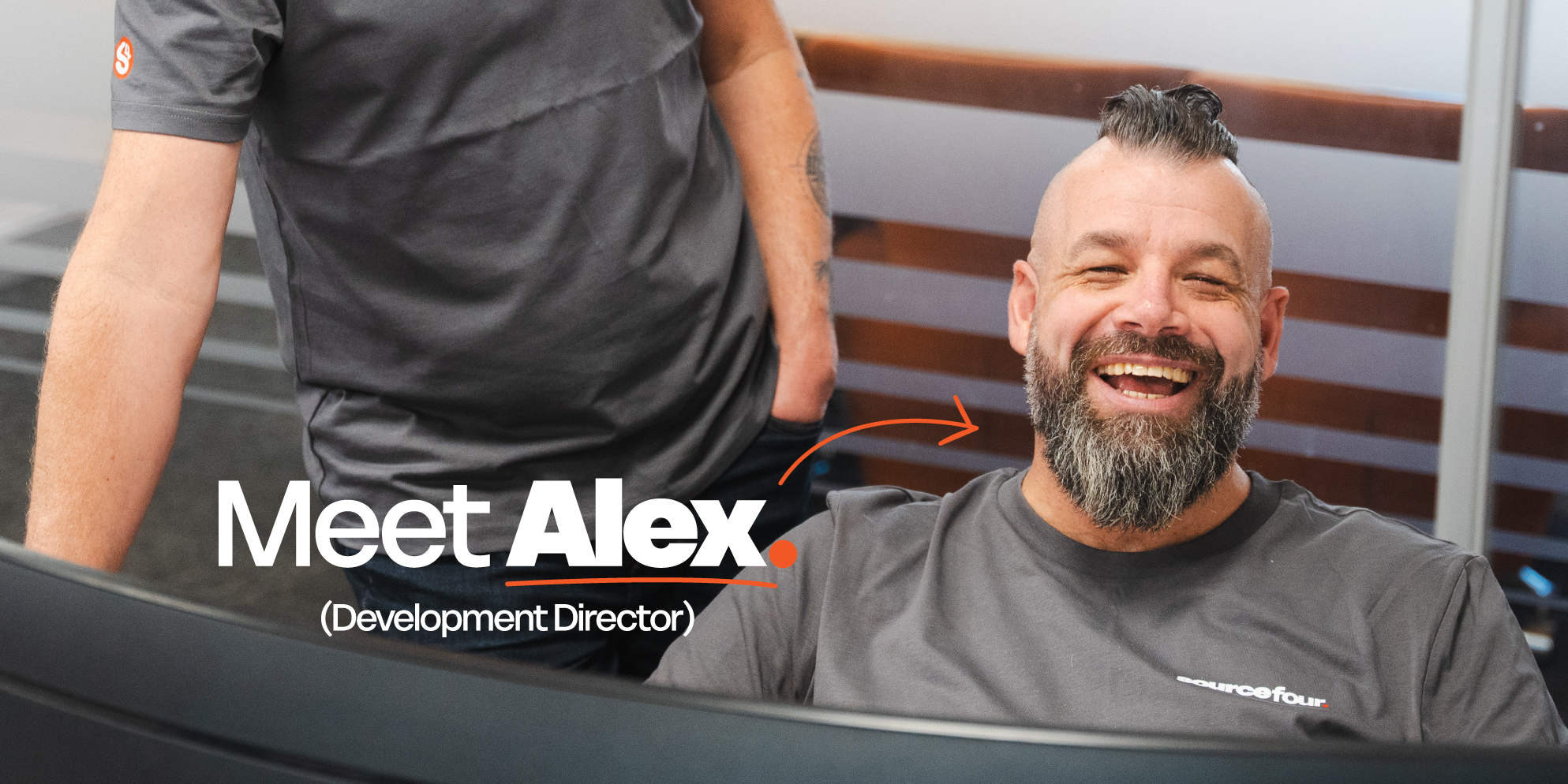 Meet the S4 Team - Sourcefour Development Director Alex leaning on a wooden fence outside of the studio, in front of a brick wall