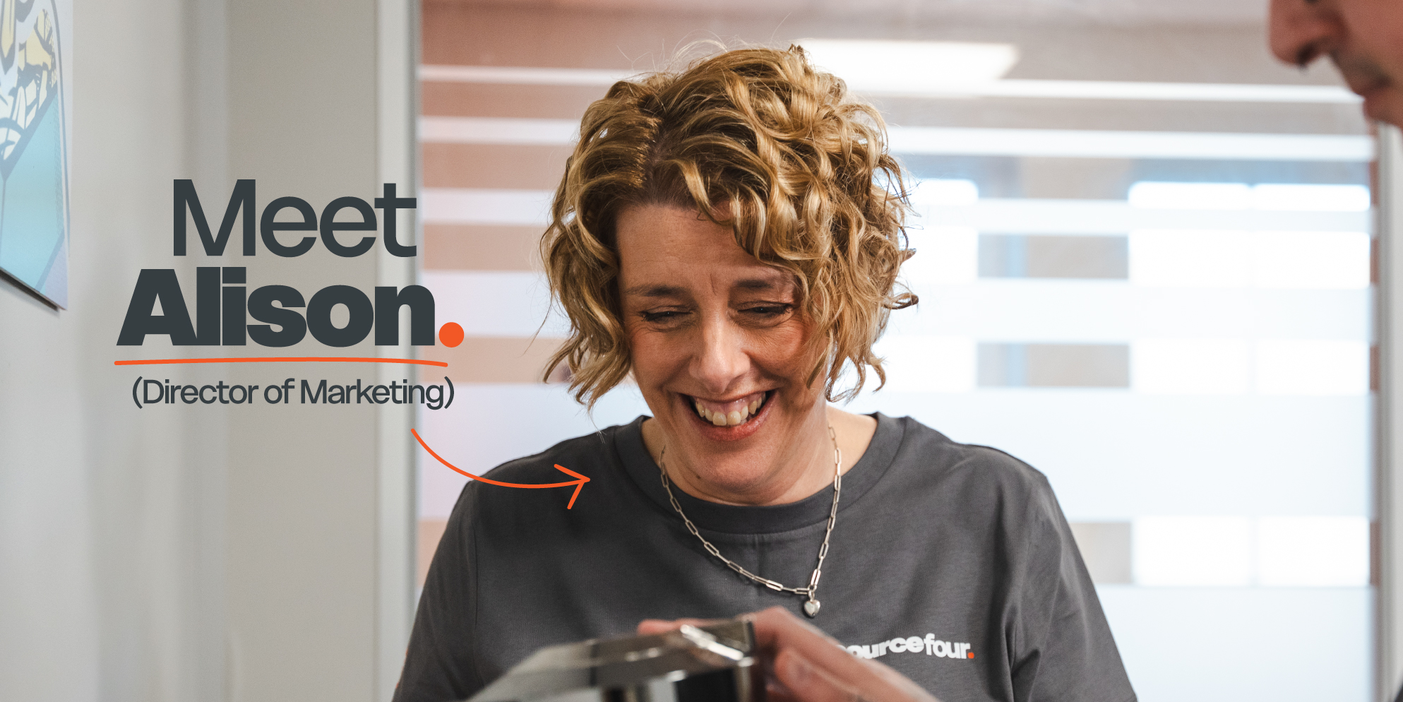 Meet the S4 Team - Sourcefour Marketing Director Alison smiling in the studio in front of the Sourcefour logo on an orange backdrop.