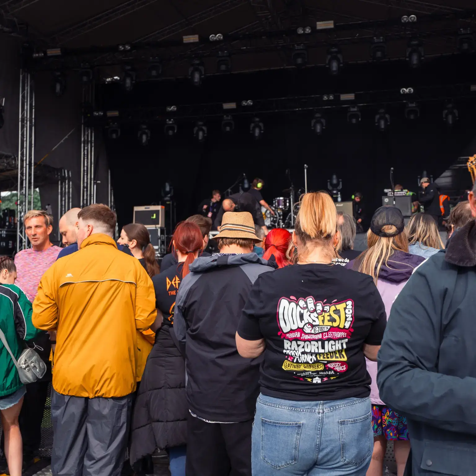 A woman in a docksfest branded t shirt, surrounded by other people enjoying a concert