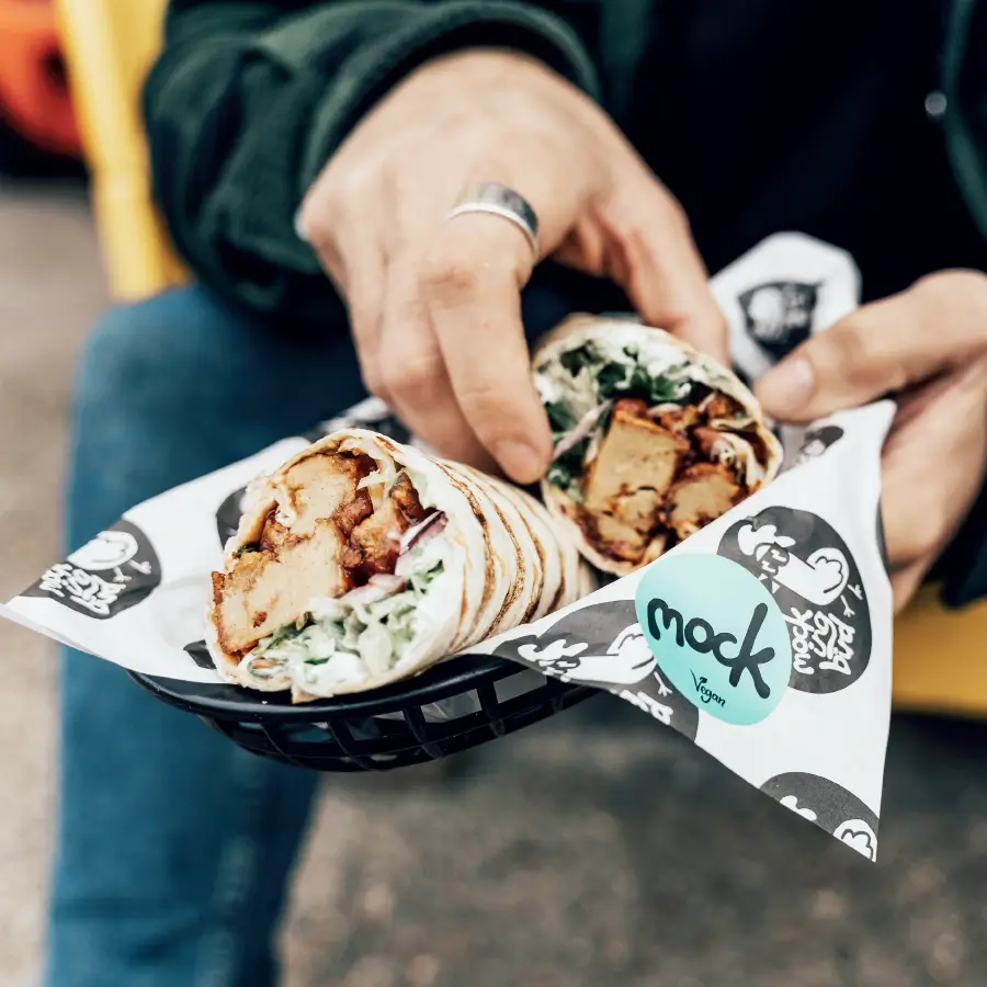 Someone grabbing Mockingbird chicken wraps out of a Mockingbird themed basket