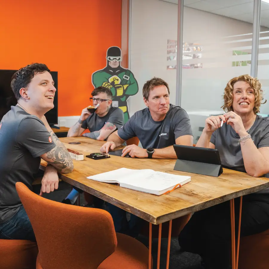 The Sourcefour team having a meeting together in an orange-themed board room